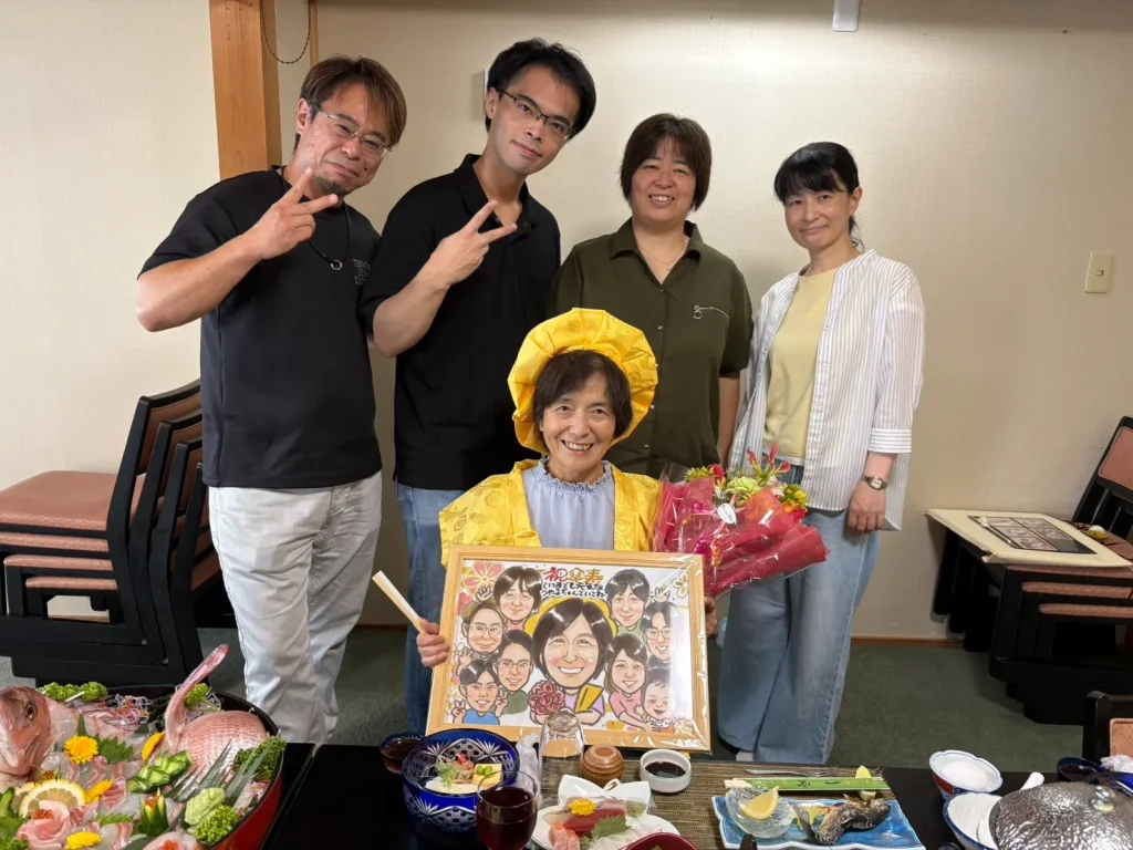 傘寿祝いの似顔絵を囲んで笑顔を見せるご家族